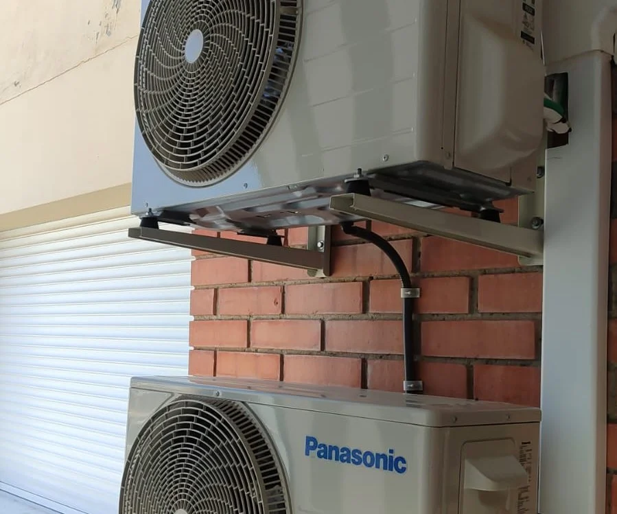 Dues unitats exteriors Panasonic muntades una sobre l’altra en una paret de maó.