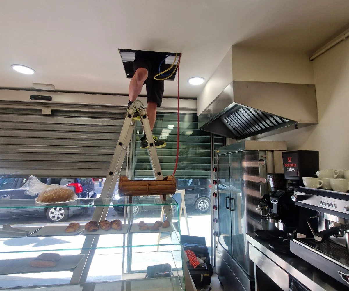 Treball de manteniment al sostre d’un bar, al costat de la campana extractora.
